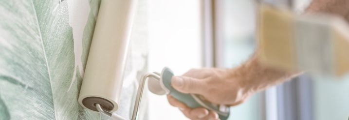 Person streicht Tapete mit Rolle glatt